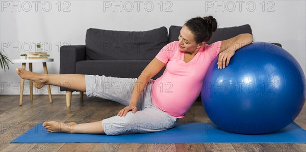 Smiley pregnant woman home with exercise ball mat
