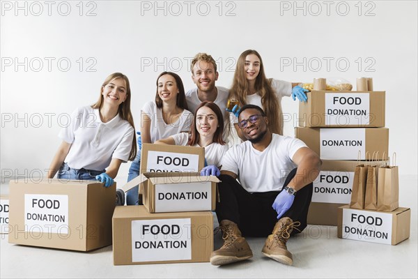 Smiley volunteers posing together with donation boxes with food