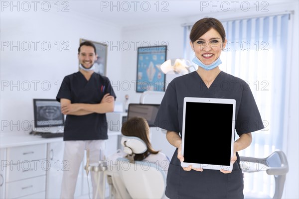 Smiling female dentist showing digital tablet clinic