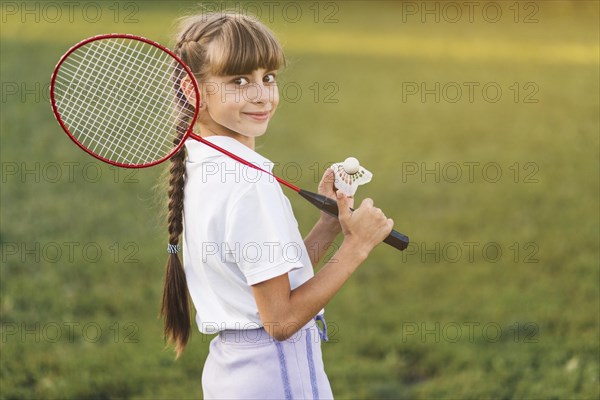 Smiling girl holding badminton her shoulder shuttlecock