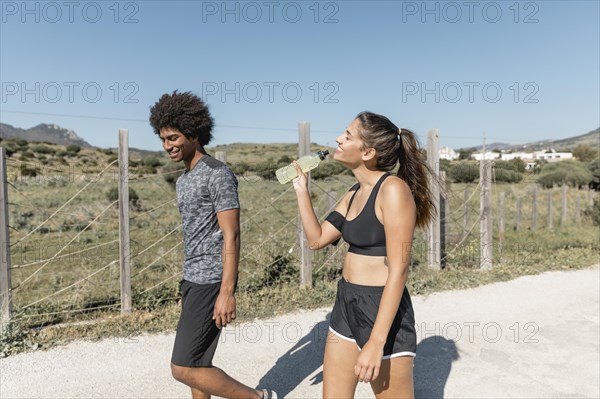 Smiling people walking while woman drinking water