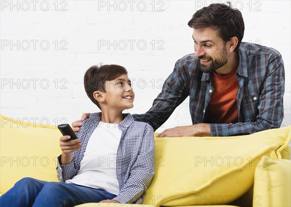 Son holding remote control looking his father