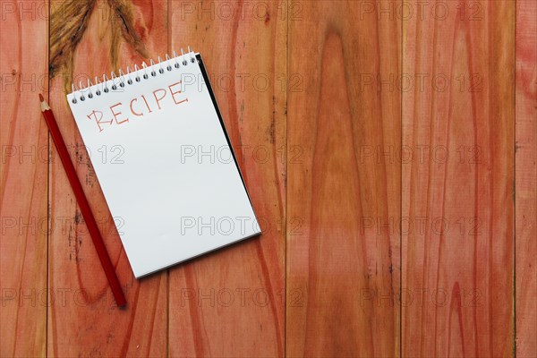 Spiral notepad near recipe word near pencil wooden background