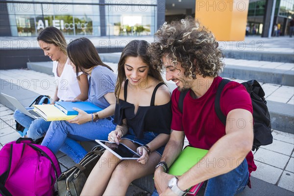 Students using tablet near friends