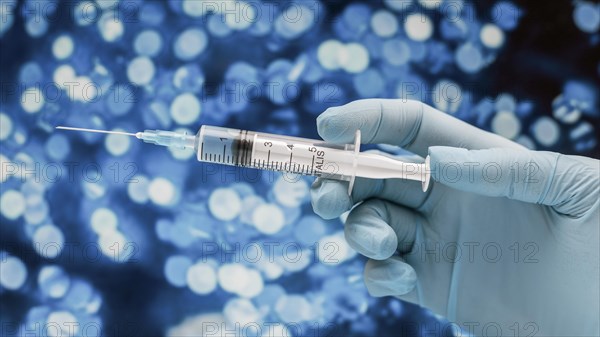 Syringe with vaccine held by hand with glove