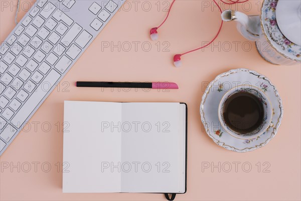 Tea earphones near notebook keyboard