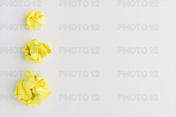 Three yellow crumpled paper ball different sizes against white background