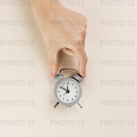 Top view hand holding tiny clock