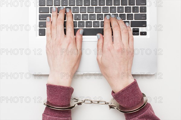 Top view hands with handcuffs working laptop