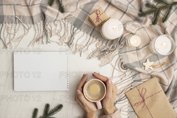 Top view person holding mug with blanket candles