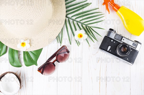 Tropical vacation arrangement with sunscreen camera hut sunglasses coconut flowers palm leaves