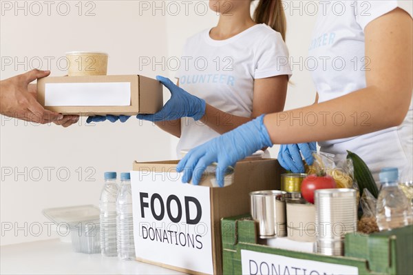 Volunteers with gloves handing boxes with food donation