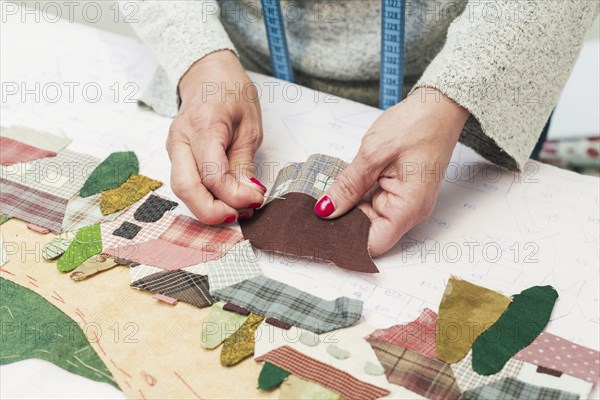 Woman s hand stitching fabric patch house with needle workplace