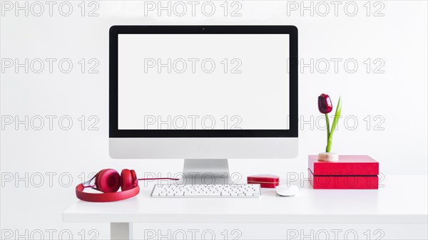 Workplace with keyboard near monitor computer mouse ornament flower headphones