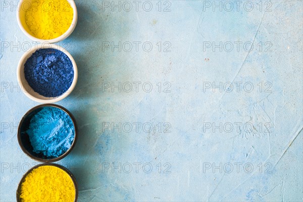 Yellow blue holi color powder bowls concrete painted background