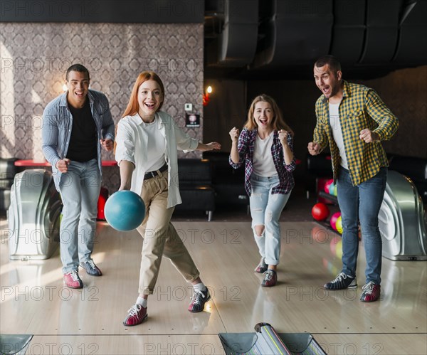 Young woman throwing bowling ball alley