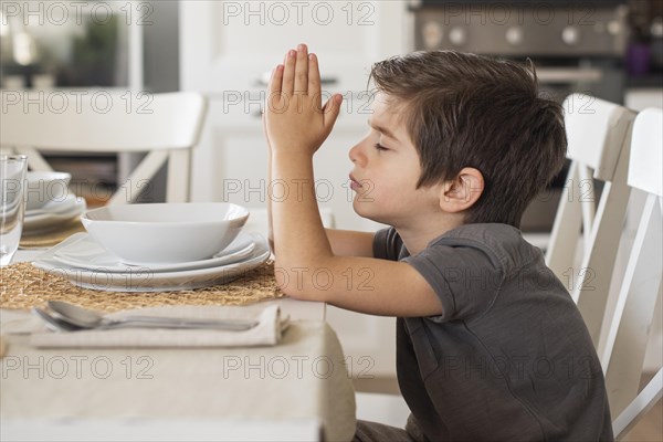 Adorable young boy praying home