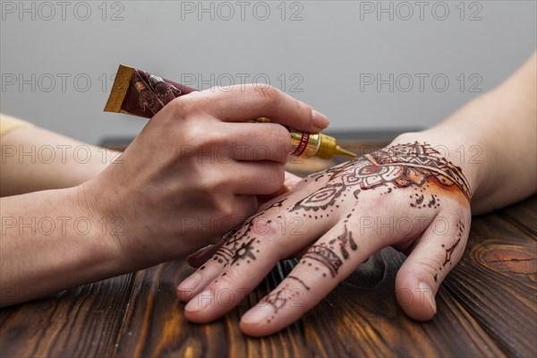 Artist making mehndi womans hand table