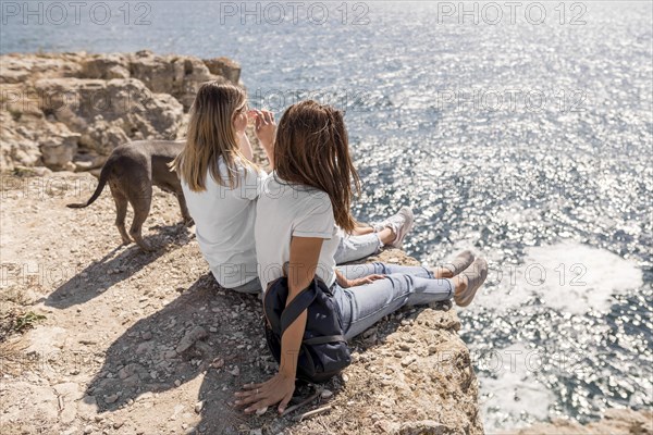 Best friends sitting rocks ocean