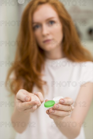 Blurred woman showing contact lens with it s container