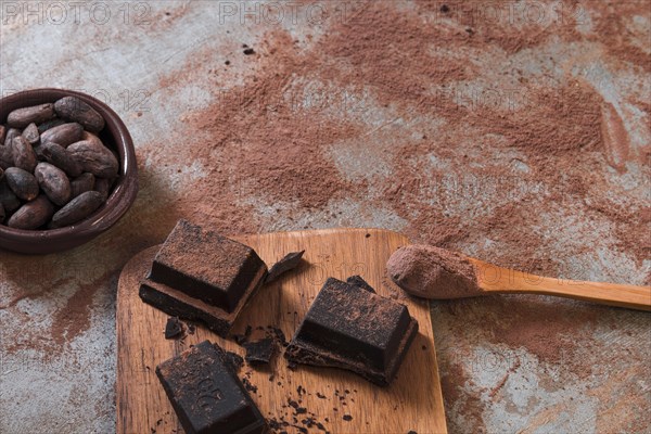 Bowl cocoa beans powder spoon with chocolate pieces