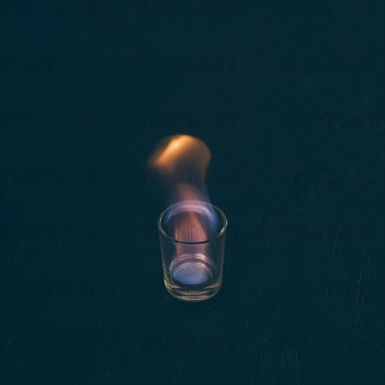 Burning tequila shot glass dark background