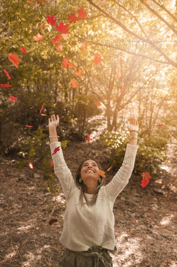 Cheerful woman throwing autumn leaves