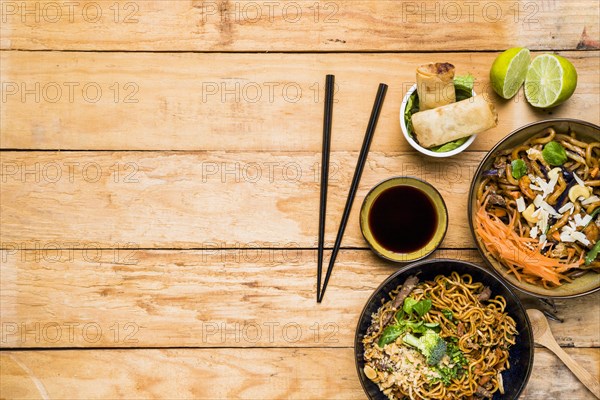 Chopsticks with spring rolls noodles sauces with chopsticks wooden table