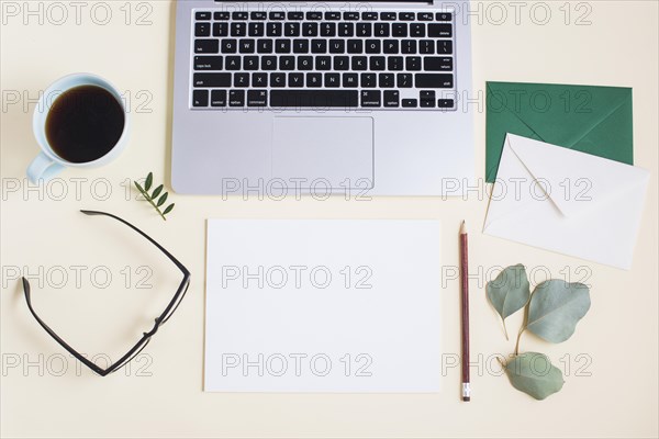 Close up laptop with envelope paper pencil eyeglasses tea cup eyeglasses colored backdrop