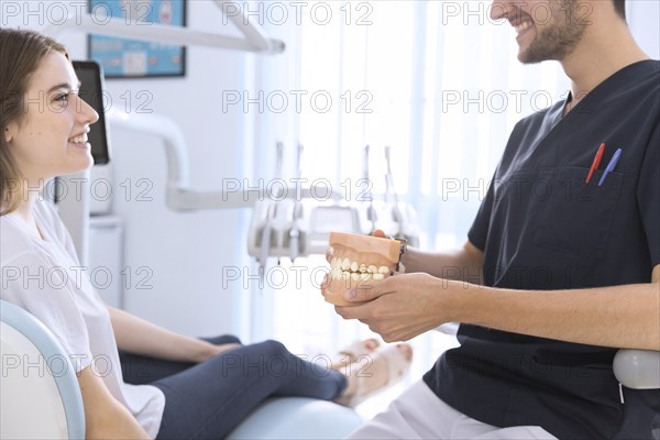 Close up male dentist showing teeth model patient