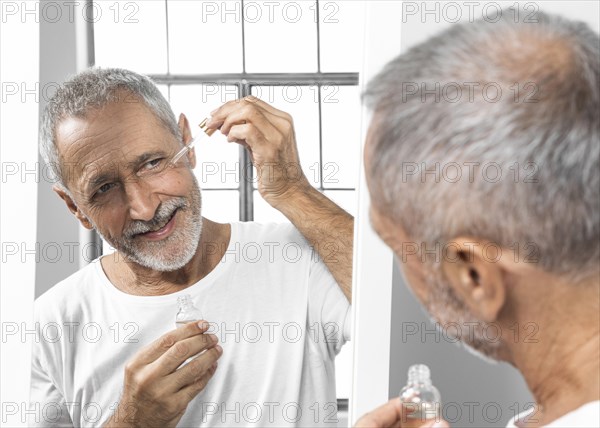 Close up man applying face serum