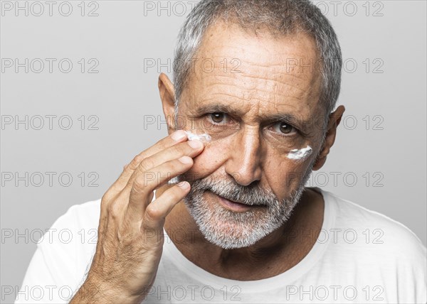 Close up old man using face cream