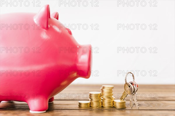 Close up pink piggybank near stacked coins key