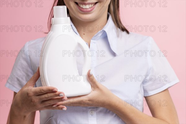 Close up smiley woman holding detergent bottle