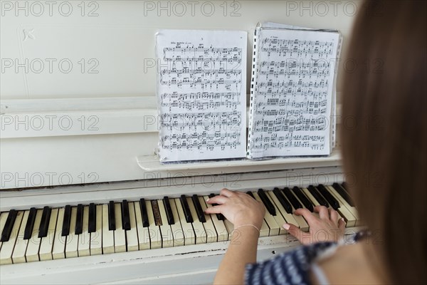 Close up woman playing piano by looking musical sheet piano