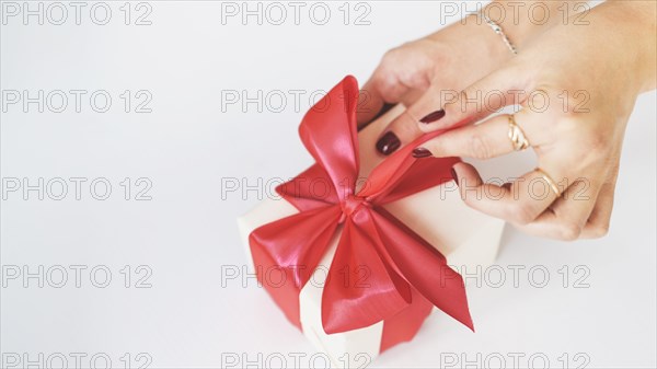 Close up woman s hand unwrapping gift box white background