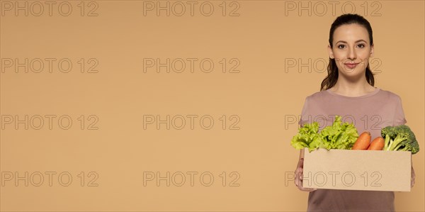 Copy space woman holding cartoon box with vegetables