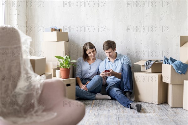 Couple looking smartphone while packing move house