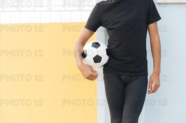 Crop black man standing holding football