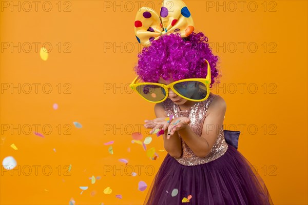 Cute girl with clown wig blowing confetti