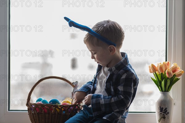 Cute little boy checking basket with eggs