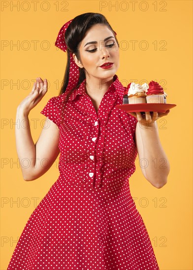 Cute pinup girl posing with cupcakes