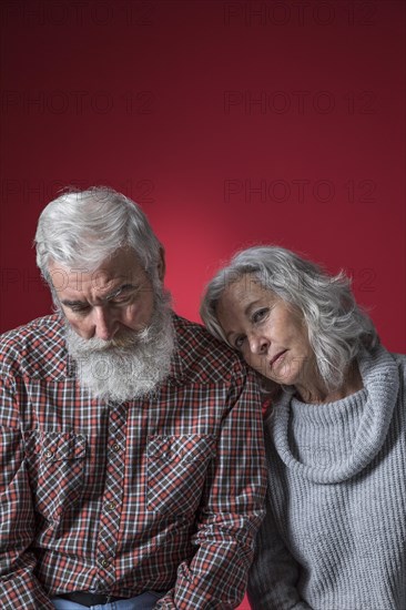 Depressed senior couple against colored background