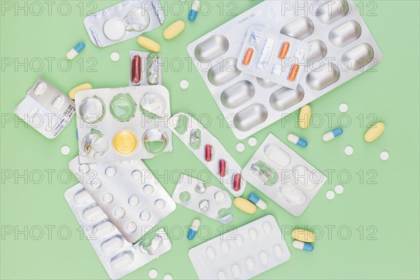 Different type medical pills out blister packed against green background