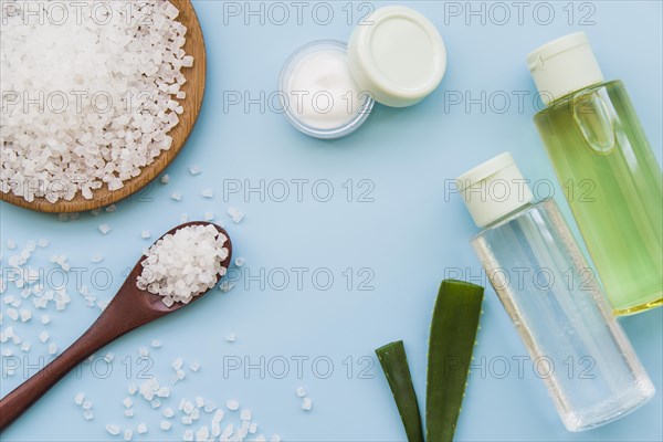 Elevated view rock salts cream aloevera spray bottles blue background