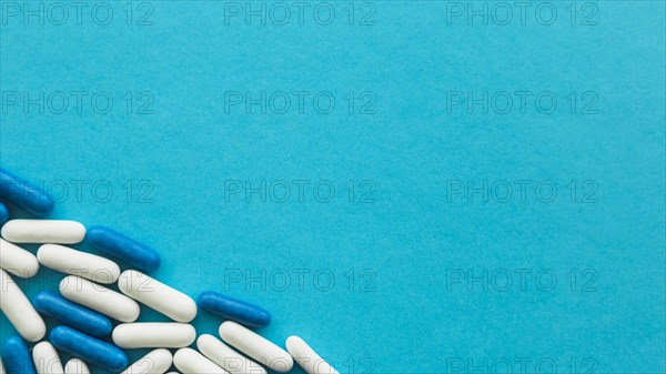 Elevated view white blue candy capsules corner cyan backdrop