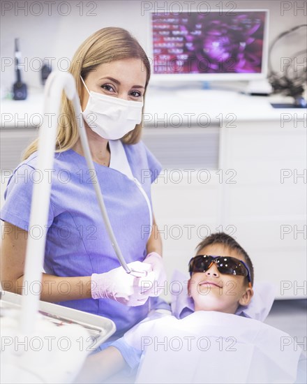 Female dentist standing near boy wearing safety protective glasses