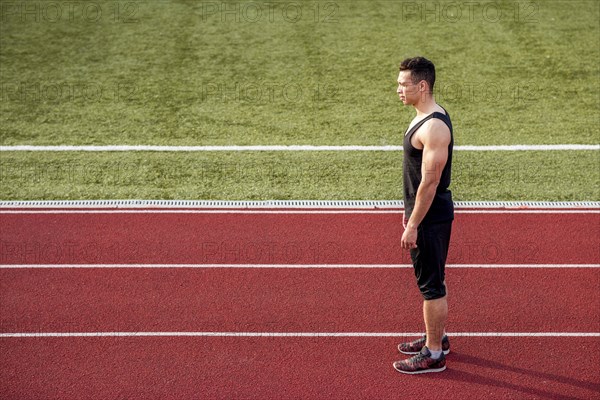 Fitness young male runner standing red running track