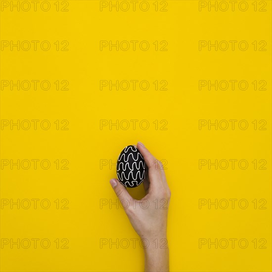 Flat lay hand holding easter egg with design