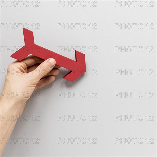 Flat lay hand holding red arrow white background